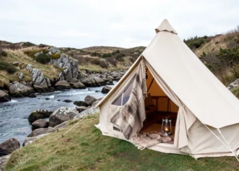 A bell tent pitched near a stream in a green countryside campsite, one of the best Places to Pitch a Bell Tent in the UK