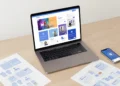 Laptop and smartphone displaying free UI mockup templates on screen with printed templates on wooden desk