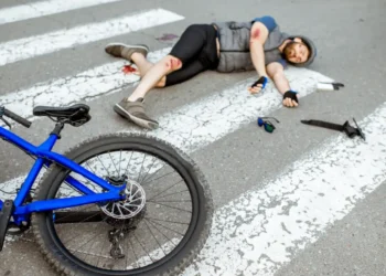 Confident cyclist standing with bicycle near law office building while checking lawyer contact information on smartphone after a Bicycle Accident Lawyer