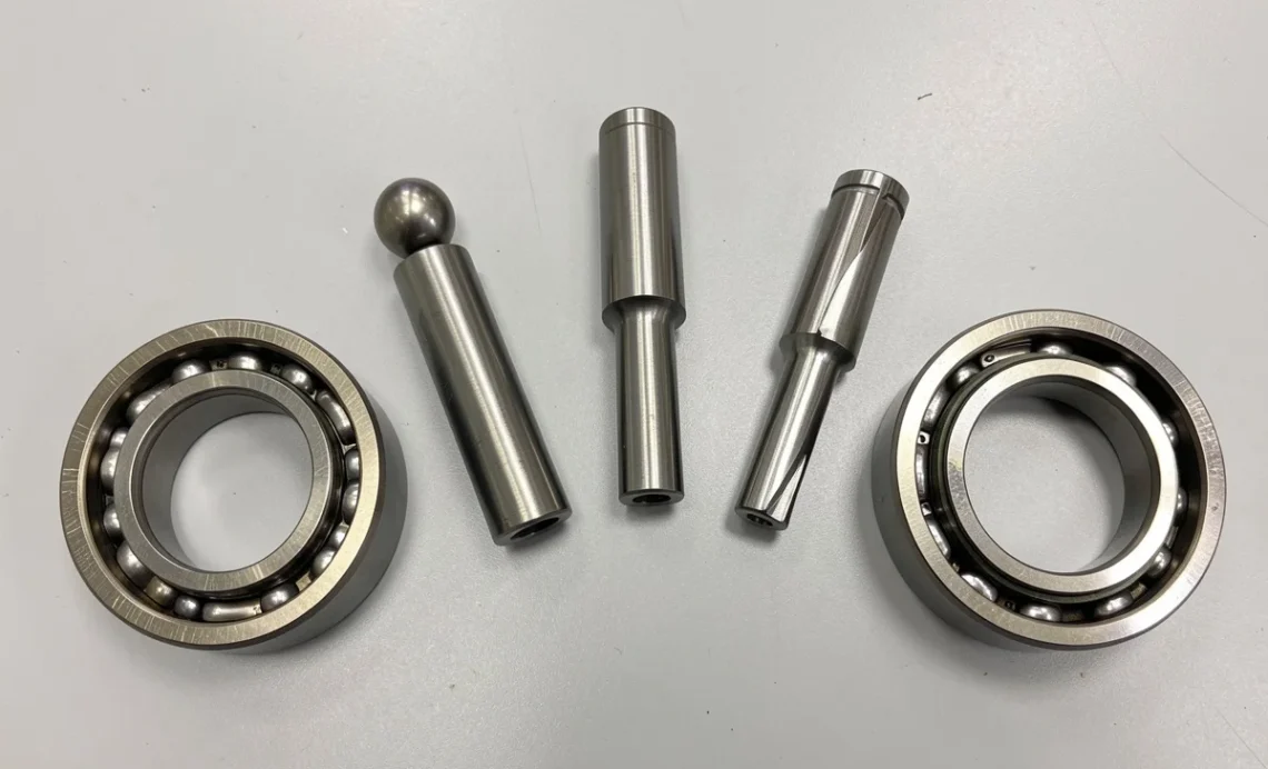 The Different Types of Bearings: How to Find a Suitable Bearing Type for Your Needs 1 Different types of bearings including ball bearing, roller bearing, tapered roller bearing, needle bearing, angular contact bearing, and ceramic bearing arranged on a workbench for a guide on choosing suitable bearing type