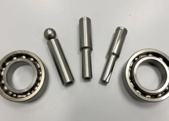 Different types of bearings including ball bearing, roller bearing, tapered roller bearing, needle bearing, angular contact bearing, and ceramic bearing arranged on a workbench for a guide on choosing suitable bearing type